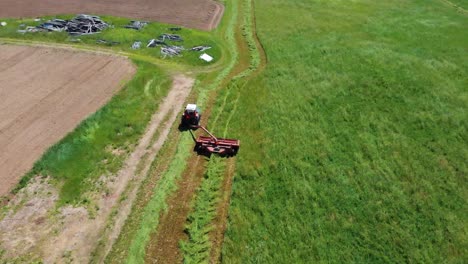 Drohne-Zieht-Hoch-Und-Weg-Vom-Traktor-Auf-Dem-Landwirtschaftlichen-Feld,-Das-Heu-Erntet