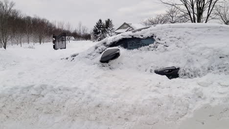 Punto-De-Vista-De-Un-Automóvil-Que-Conduce-A-Través-De-Un-Camino-Nevado-Que-Pasa-En-Un-Automóvil-Cubierto-De-Nieve-Después-De-Una-Ventisca-De-Nieve-Invernal-En-Fort-Erie,-Ontario,-Canadá