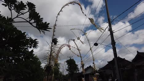 Local-Street-with-Penjor-Decoration-for-Balinese-Galungan-Celebration,-Bali-Hinduism,-Daytime,-Blue-Sky-in-Traditional-Village,-Gianyar,-Sukawati