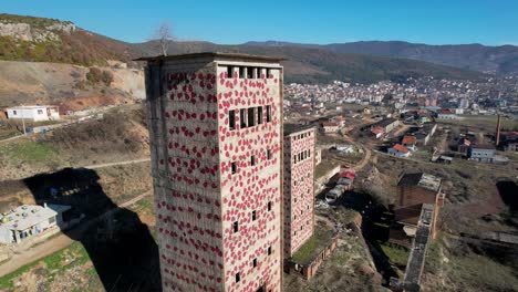 Altas-Torres-De-Fábrica-Abandonada,-Paredes-Pintadas-Con-Bichos-Rojos-Cerca-De-Perrenjas-En-Albania