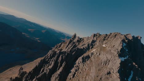Cinematic-fpv-flight-over-peak-of-rocky-mountains-in-Norway-during-golden-sunset