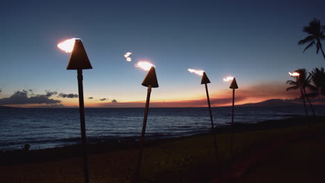 Antorchas-Tiki-Con-Fuego-Por-La-Noche-En-La-Playa-Tropical-En-Wailea,-Maui,-Hawaii