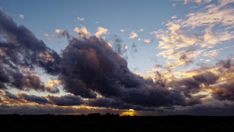 Timelapse-taken-by-drone-shows-clouds-colored-by-the-rays-of-the-sunset,-with-changing-shapes-and-colors-while-flying-over-the-landscape,-offering-a-breathtaking-view-of-the-clouds-and-the-sunset