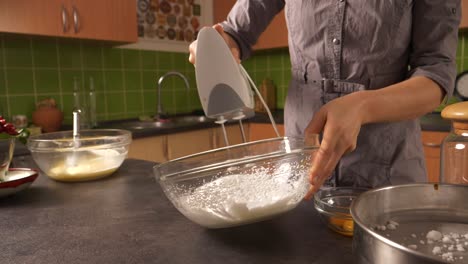 A-close-up-shot-of-a-young-woman-using-an-electric-mixer-mixing-vanilla-sugar,-salt-and-egg-whites-to-create-foam-for-a-cake-filling