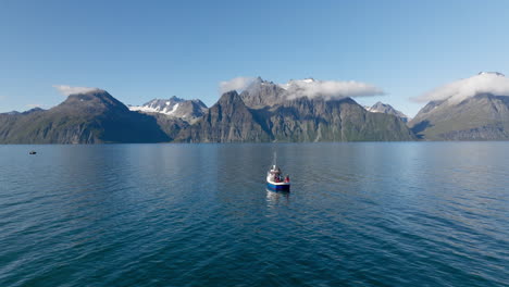 Fishing-boat-in-calm-arctic-sea-with-scenic-mountain-backdrop,-Lyngen