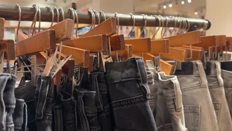 Close-up-rack-of-jeans-clipped-on-hangers-on-display-in-store,-clearance-sale