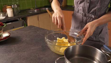 Close-up-shot-of-a-young-woman-mixing-butter-with-honey-preparing-a-honey-cake-filling