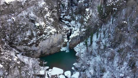 remote-shot-of-waterfall-in-snowy-air,-drone-flying-overhead-in-amazing-landscape