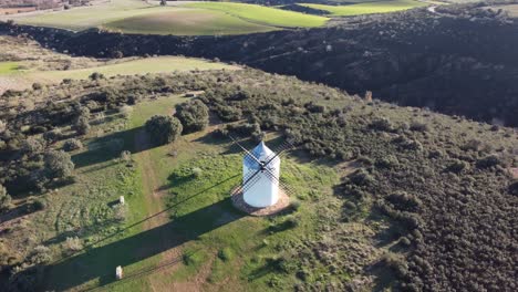 Luftaufnahme-Traditionelle-Alte-Windmühle,-Umgeben-Von-Grünen-Wiesen-Und-Goldenem-Tageslicht