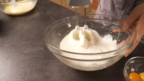 A-close-up-shot-of-a-young-woman-using-an-electric-mixer-beating-the-egg-white-to-create-foam-for-a-cake-filling