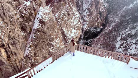girl-watching-the-view-in-the-canyon,-drone-rising,-kastamonu-turkey-valla-canyon-in-snowy-winter-season