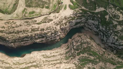 Aerial-overhead-shot-of-the-canyon-Wied-il-Għasri-with-a-beautiful-clear-turquoise-water