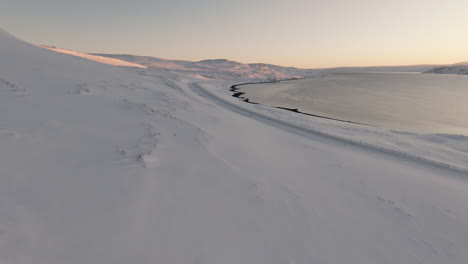 Beautiful-black-sand-beach-shore-covered-in-snow,-winter-landscape,-dolly
