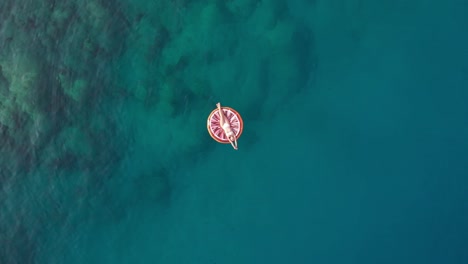 Im-Sommer-Liegt-Das-Mädchen-Auf-Dem-Bunten-Meeresboden,-Die-Drohne-Schießt-Nach-Oben-Auf-Den-Meerestruthahn
