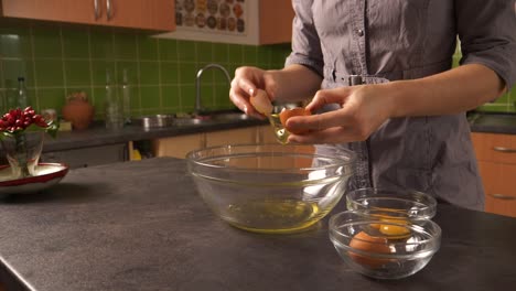 Close-up-shot-of-a-young-woman-cracking-eggs-and-separating-yolk-and-egg-white-into-glass-bowls