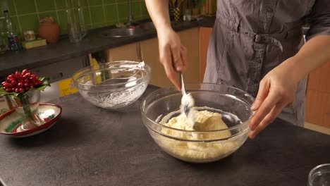 Slow-zoom-in-close-up-shot-of-a-young-woman-mixing-the-egg-white-foam-into-the-mixture-of-butter-and-honey-preparing-a-honey-cake-filling