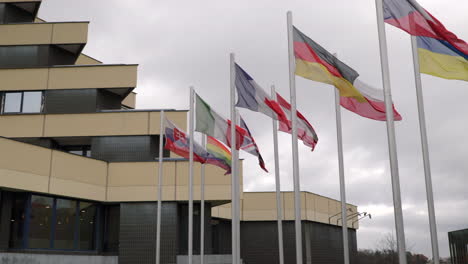 National-flags-in-the-wind-in-front-of-a-hotel-building-on-a-cloudy-day