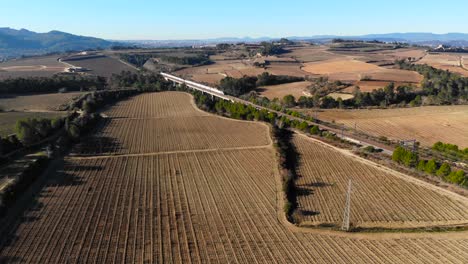 Aerial:-double-decker-high-speed-train-in-Spain-among-vineyards-between-Barcelona-and-Madrid,-in-Catalonia