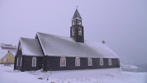 Slow-motion-video-of-a-snow-covered-church-on-the-coast-in-a-blizzard-in-Ilulissat,-Greenland