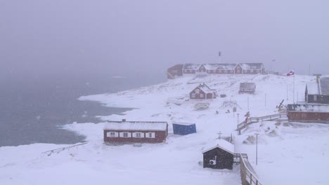 Slow-motion-video-of-red-houses-on-the-arctic-coast-in-a-snowstorm-in-Ilulissat,-Greenland
