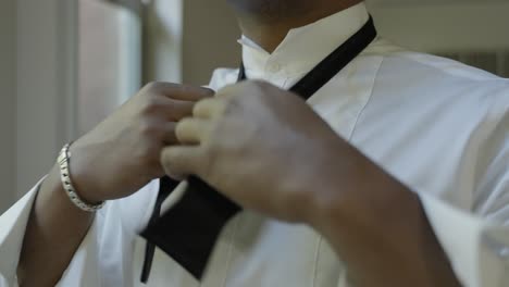 Groom-getting-ready-on-his-wedding-day,-tying-bow-tie