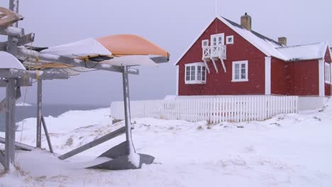 Slow-motion-video-of-canoes-in-front-of-a-red-house-on-the-coast-in-a-snowstorm