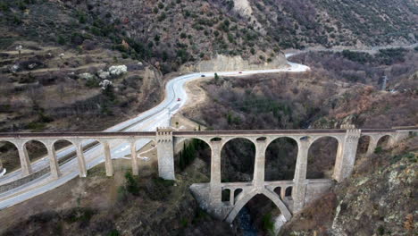 Aerial-view-of-the-Séjourné-Bridge-that-goes-above-a-highway-and-a-cliff-in-Fontpédrouse,-France