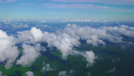 Eine-Wunderschöne-Szene-Aus-Wolken-Und-Einer-Bewaldeten-Küste,-Wie-Sie-Aus-Dem-Fenster-Eines-Flugzeugs-Bei-Tageslicht-Zu-Sehen-Ist