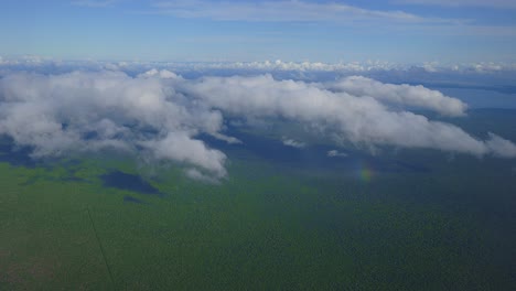 Eine-Luftperspektive-Von-Wolken,-Die-Tagsüber-über-Einer-Grünen-Küstenlandschaft-Schweben