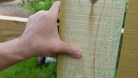 Man-using-pneumatic-nail-gun-on-wooden-fence,-close-up-view