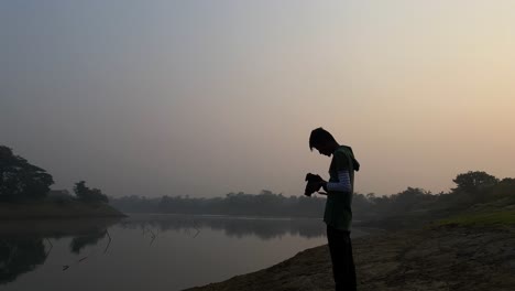 Photographer-standing-takes-photos-of-river-on-a-foggy-winter-morning,-Sylhet
