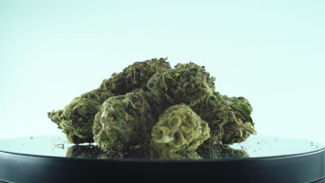 Close-up-shot-of-a-Marijuana-sativa-Super-Lemon-Haze-flowers,-green-weed,-purple-Kush,-on-a-reflecting-360-rotating-stand,-Slow-motion-4K-video