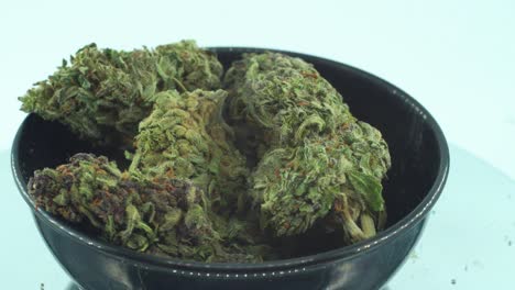 Close-up-shot-of-a-Marijuana-sativa-Super-Lemon-Haze-flowers,-green-weed,-purple-Kush,-on-a-reflecting-360-rotating-stand,-in-a-black-shiny-bawl,-Slow-motion-4K-video