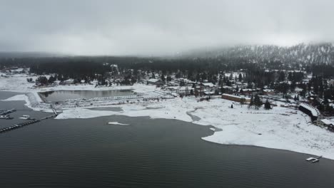 Aerial-View-of-Big-Bear-Lake-and-Village-Harbor-on-Cold-Winter-Day,-Snow-Capped-Coast-and-Marina,-California-USA