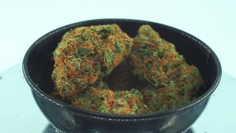 Close-up-shot-of-a-Marijuana-sativa-Super-Lemon-Haze-flowers,-orange-strains,-green-weed,-on-a-reflecting-360-rotating-stand,-in-a-black-shiny-bawl,-Slow-motion-4K-video