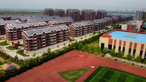 Vista-Aérea-De-Un-Complejo-Residencial-Urbanizado-Con-Un-Campo-De-Fútbol-En-El-Nuevo-Distrito-De-Nanhai,-China