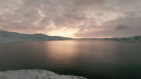 Dolly-forward-towards-bright-sunrise-above-ocean-in-winter-landscape