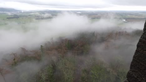 Static-shot-of-fog-rolling-in-over-the-forest-towards-the-Wallace-Monument-in-Stirling
