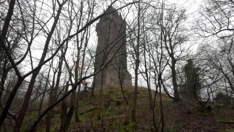 Tilting-shot-of-the-National-Wallace-Monument-from-the-woodland-with-fog-surrounding