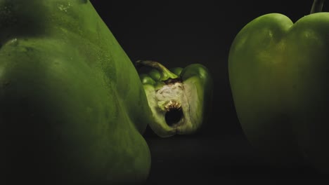 Three-fresh-green-bell-peppers,-one-sliced-open