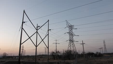 Transmission-towers-and-electrical-lines-silhouetted-with-setting-sun-in-background