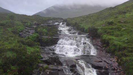 Luftaufnahme-Des-Wasserfalls,-Der-Schroffe-Felsen-Auf-Der-Isle-Of-Skye,-Schottland,-Hinunterstürzt