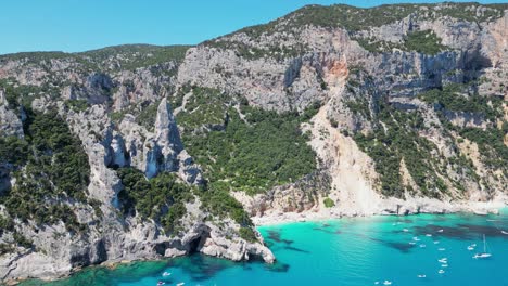 Touristenboote-Genießen-Sommerferien-Am-Strand-Von-Cala-Goloritze-Und-Felsformation-In-Sardinien,-Italien---Antenne-4k