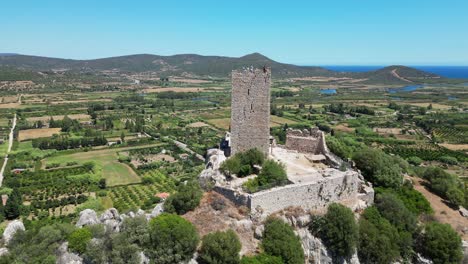 Group-of-Tourist-People-Enjoy-View-at-Posada-Tower-in-Sardinia,-Italy---Aerial-4k