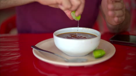 Close-up-slow-motion-of-a-Latin-man-squeezing-lime-into-his-barbacoa-broth-in-a-restaurant-in-Mexico