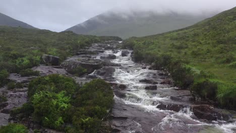 Luftaufnahme-Von-Wasser,-Das-Schroffe-Felsen-In-Isle-Of-Skye-Hinabstürzt