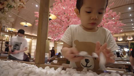 A-three-year-old-Chinese-Indonesian-boy-is-playing-with-stone-ornaments-in-a-Japanese-themed-restaurant