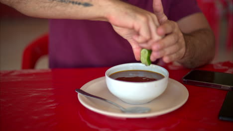 Zeitlupe-Eines-Lateinamerikanischen-Mannes,-Der-In-Einem-Mexikanischen-Restaurant-Auf-Einem-Roten-Tisch-Eine-Limette-In-Seine-Brühe-Drückt