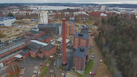 Aerial-shot-of-a-red-brick-chimney-of-an-old-factory-in-middle-of-a-construction-site