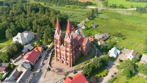 Majestic-tall-church-in-small-township-of-Sveksna,-Lithuania,-aerial-orbit-view